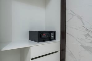 A white wall with a marble pattern and a small black device on a white shelf.