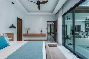 A modern bedroom with a bed, bedside table, and a ceiling fan. - Two Flamingo Villa 1 (Phuket)