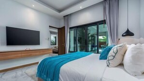 A modern bedroom with a large bed, a flat-screen TV mounted on the wall, and a sliding glass door leading to a balcony. - Two Flamingo Villa 1 (Phuket)