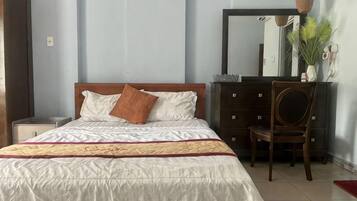 A bedroom with a bed, a dresser, a chair, and a mirror.