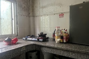 Una cocina con estufa a gas, un refrigerador y varias botellas sobre la encimera.
