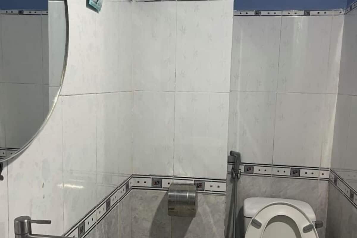 A restroom with white tiled walls, a white toilet, and a handrail.