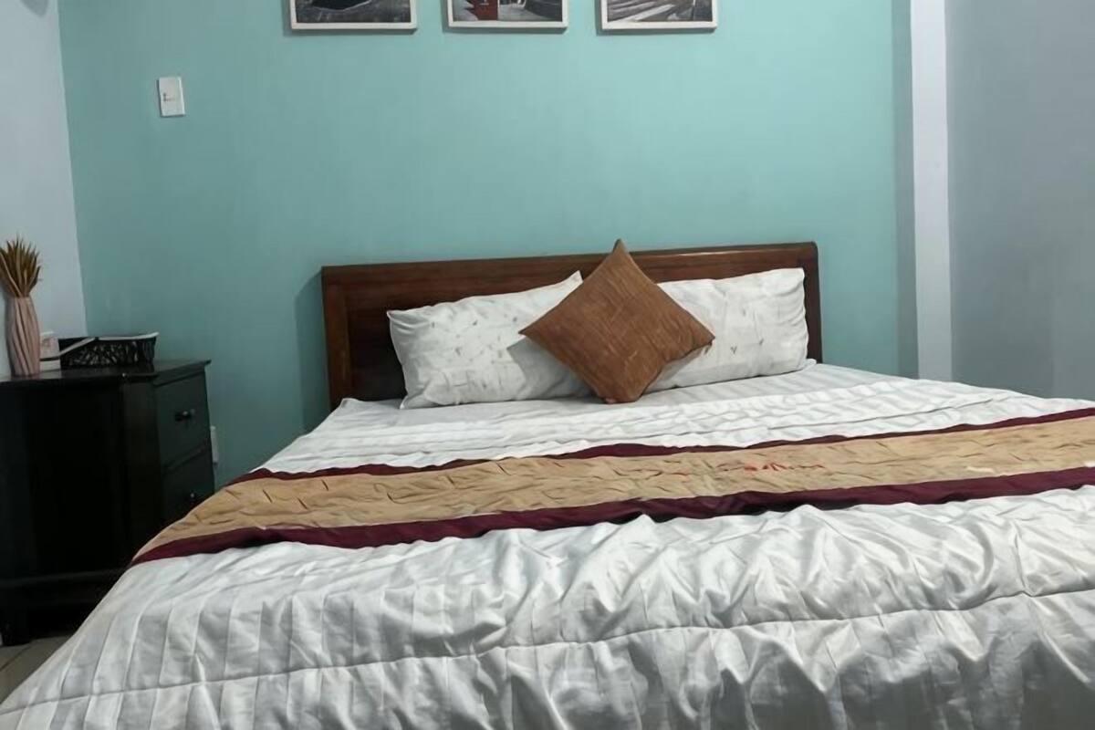 A bed with a wooden headboard, a white comforter, and a brown pillow.