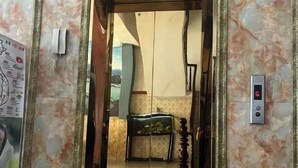 Um elevador com parede de mármore e painel digital.