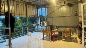 Varanda ampla com mesa e cadeiras, um cabide suspenso e um aparelho de ar condicionado.