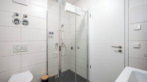 Une salle de bain moderne dotée d’une douche à parois de verre, de toilettes et d’un bidet.