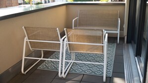 Un balcon avec deux fauteuils en osier et un tapis à motifs.