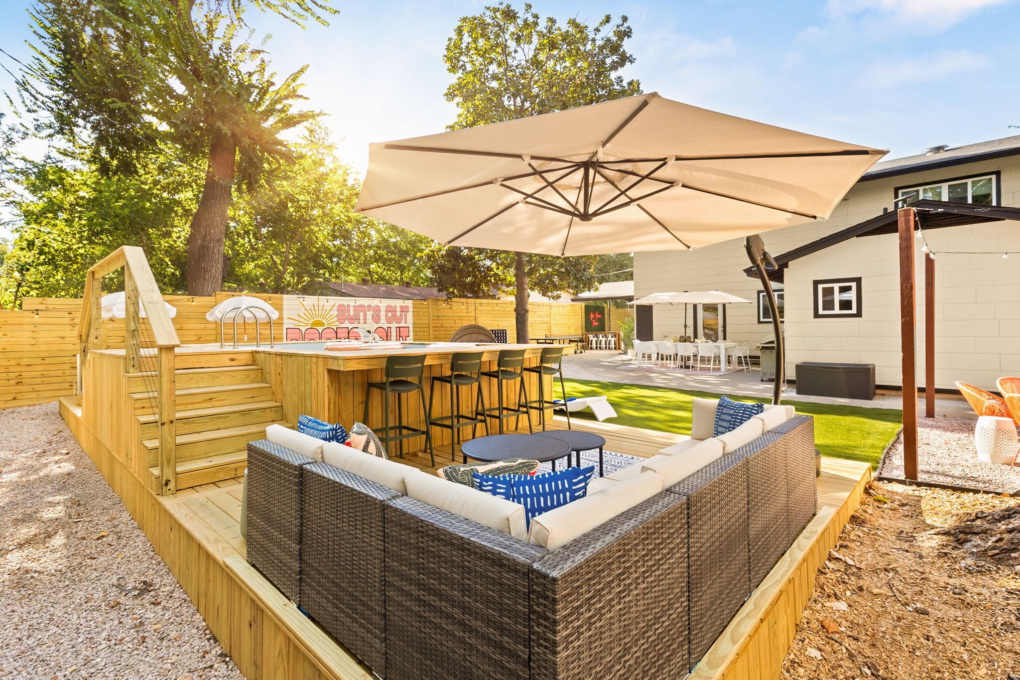 Una terraza de madera con una zona de estar integrada, una mesa y una sombrilla.
