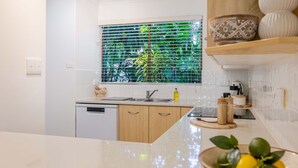Una cocina moderna con lavavajillas integrado, un lavamanos de acero inoxidable y una ventana con vistas a zonas verdes.
