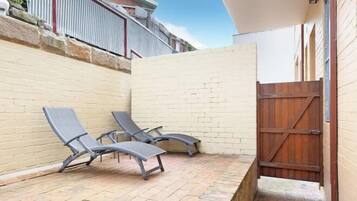 Un patio con dos sillones, un muro de ladrillo y un portón de madera.