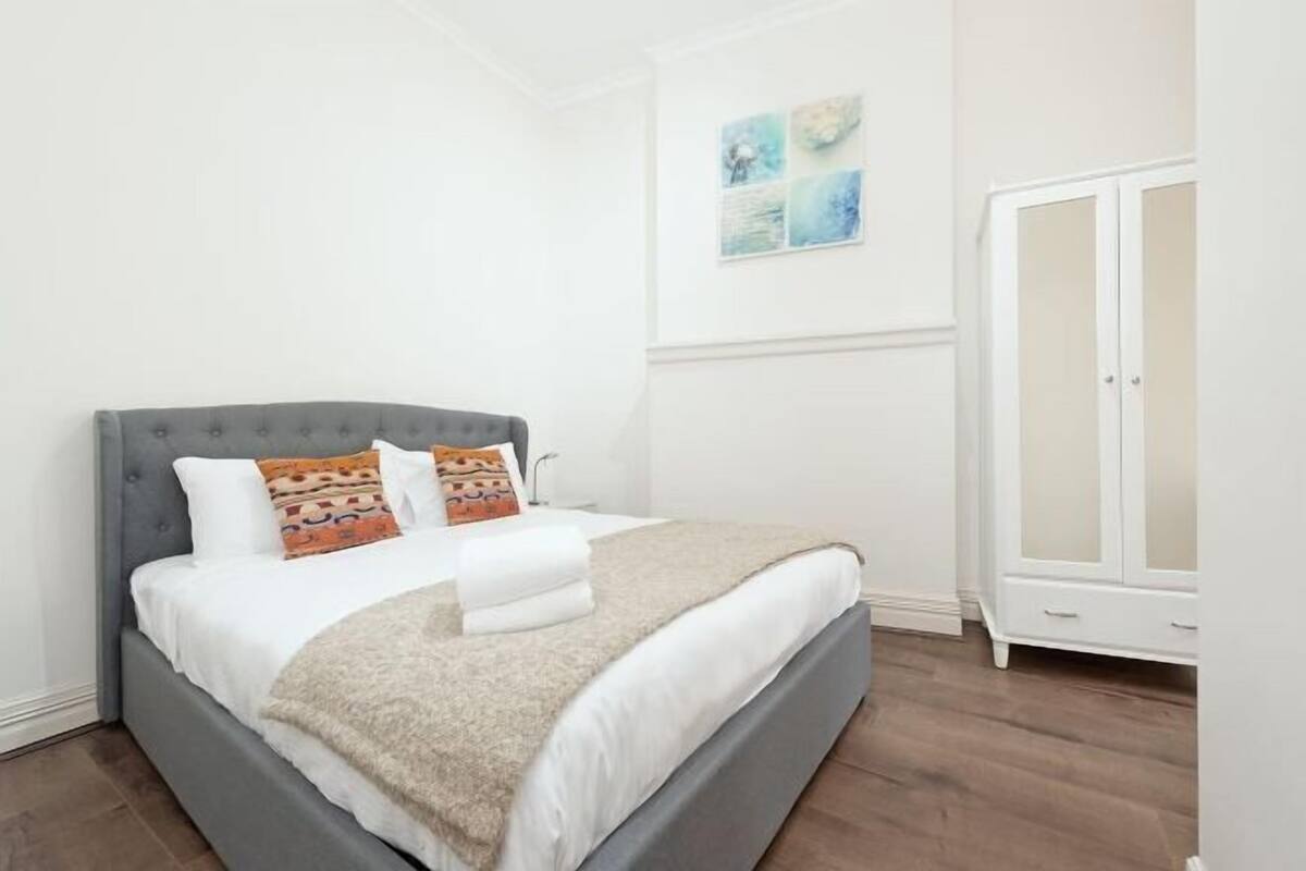 Une chambre à coucher avec un lit, une armoire et un mur décoré d’œuvres d’art.