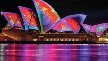 La Casa de la Ópera de Sydney de noche, con su distintivo diseño en forma de vela iluminado.