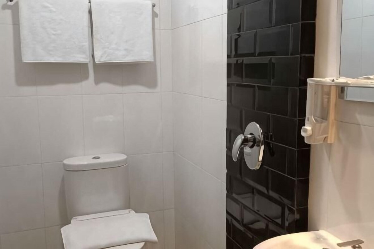 Ένα μπάνιο με τουαλέτα, νιπτήρα και καθρέφτη.