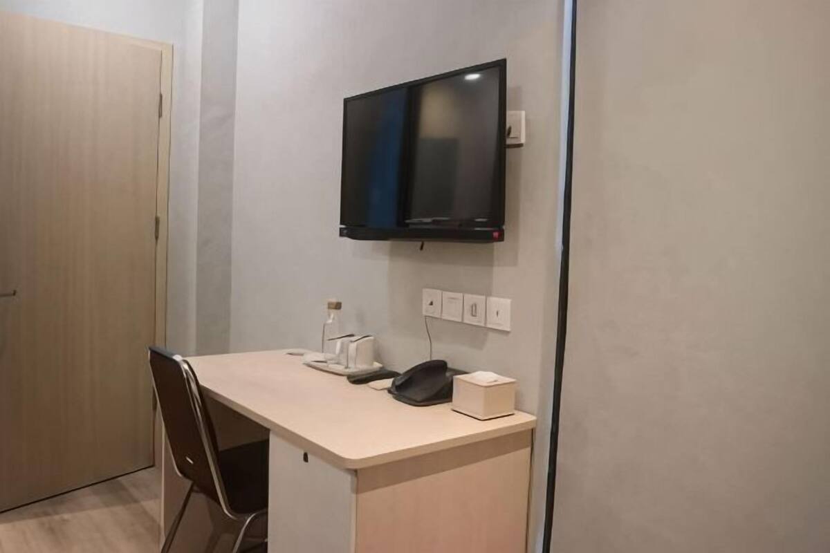 A room with a desk, chair, television, and a door.