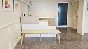 Ein Flur mit einer Bank, ein Küchenbereich mit weißen Schränken und eine Tür zu einem weiteren Zimmer.