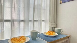 A breakfast setup with two plates of pastries and two mugs on a wooden table by a window with sheer curtains. - Nestay apartment Tokyo Itabashi (Tokyo)
