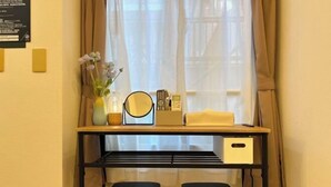 A desk with a mirror, remote controls, and a vase with flowers. There are two black stools in front of the desk. - Nestay apartment Tokyo Itabashi (Tokyo)
