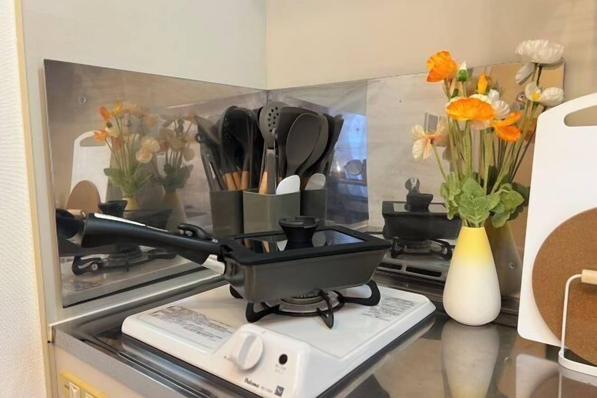 Una cocina con estufa portátil, placa de inducción blanca y un florero con flores.