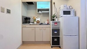 A compact kitchenette with a microwave, a small refrigerator, and a cabinet with kitchen utensils. - Nestay apartment Tokyo Itabashi (Tokyo)