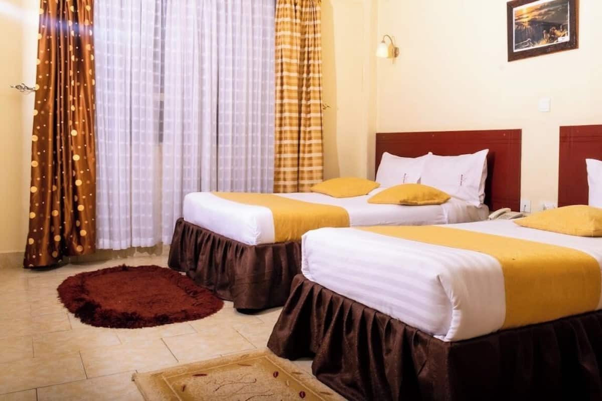 Two single beds with brown skirts, white bedding, and yellow pillows.