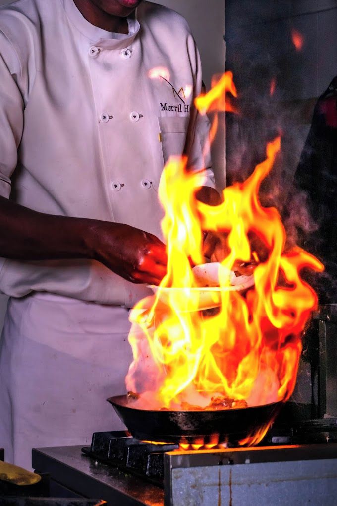 A chef cooking with a wok on a stove.
