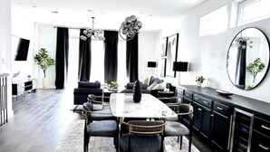 A modern dining area with a rectangular table, black upholstered chairs, and a chandelier. - Luxe 3Bed Townhome in Heights with WiFi, Private Rooftop, Private Parking (Houston)