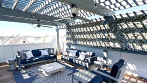 A rooftop terrace with a blue sofa, white and blue cushions, a small table, and wicker chairs. - Luxe 3Bed Townhome in Heights with WiFi, Private Rooftop, Private Parking (Houston)