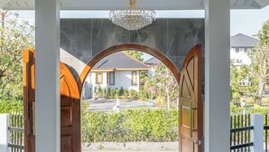 Una entrada techada con un candelabro, vista de una casa y un camino pavimentado.