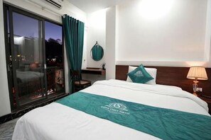 A hotel room with a bed, a nightstand, a lamp, a chair, a window with curtains, and a view of the outside. - Sapa Cosy Hotel (TT. Sa Pa)