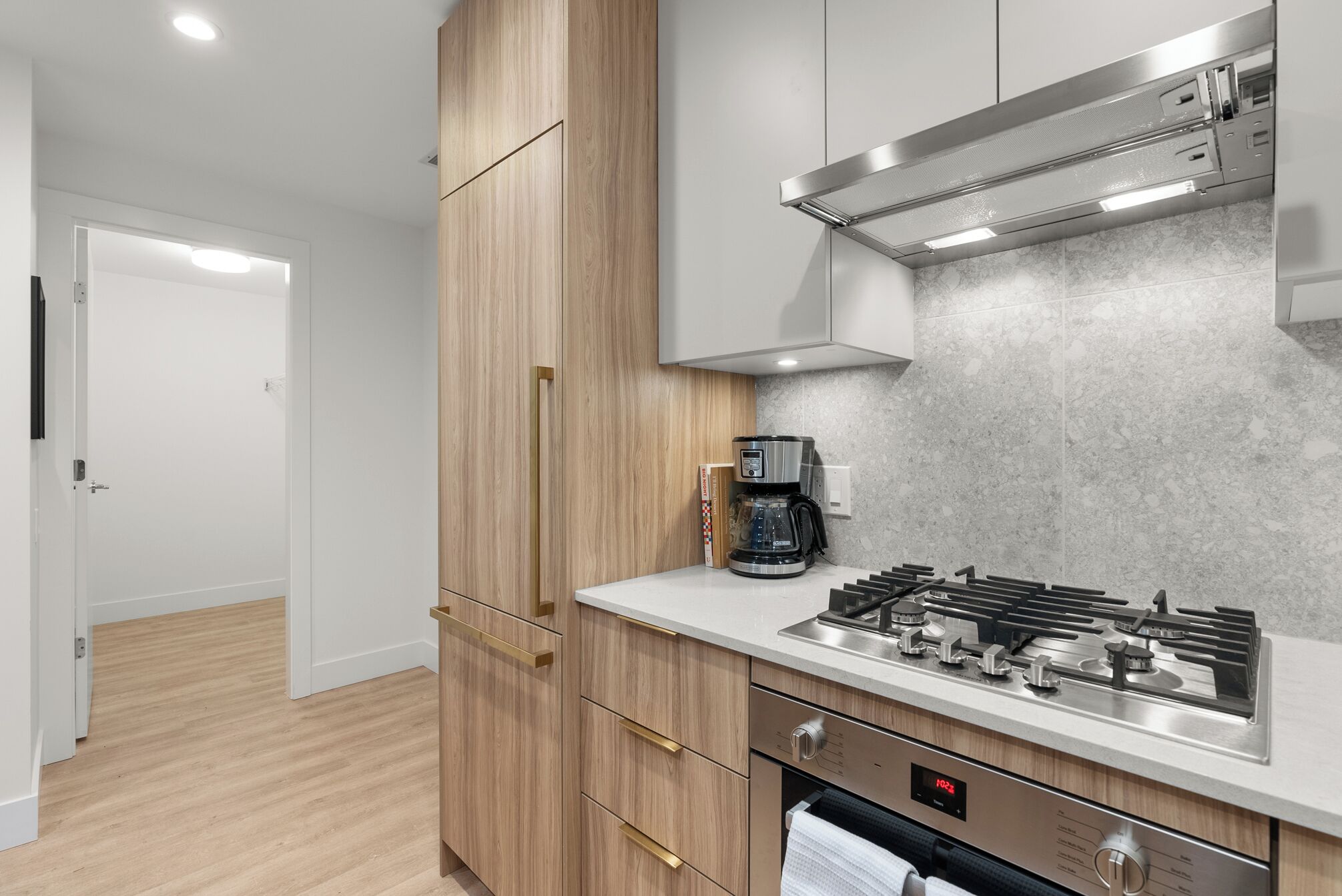 Una cocina moderna con armarios de madera, estufa a gas y cafetera.