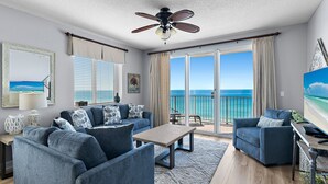 A living room with a large window, a ceiling fan, and a view of the ocean. - *Majestic Sun A801*Updated*Heated Pools +Hot Tubs*Gym*Pickleball & Tennis* (Miramar Beach)