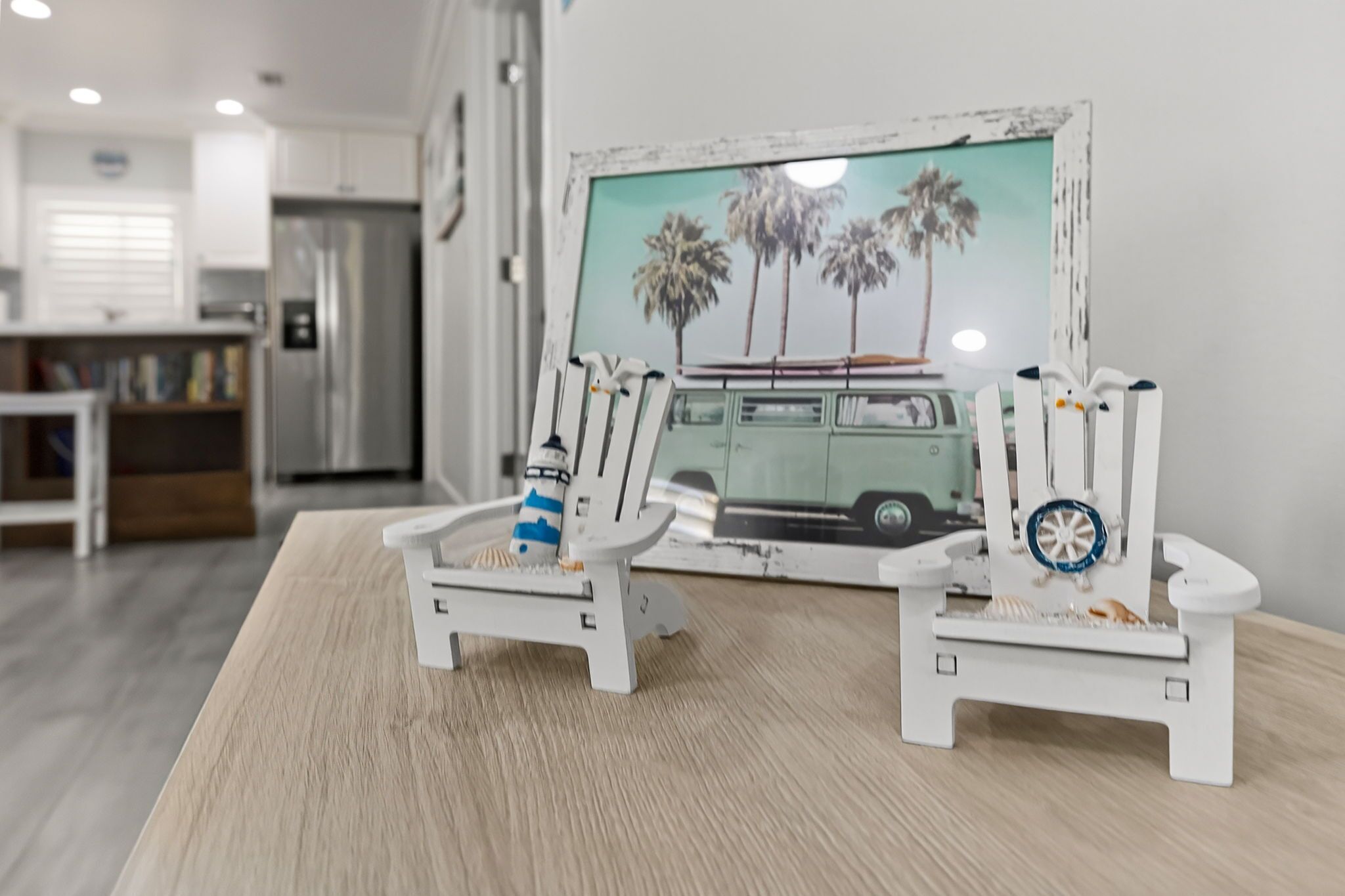 Twee witte stoelen met een surfplank en een blauwe fles op een houten tafel.