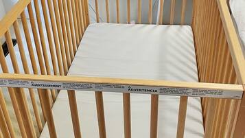 A wooden crib with a mattress and a safety label.