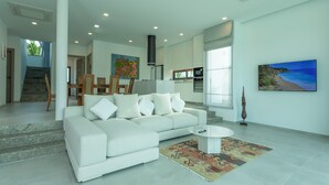 A modern living room with a white sofa, a coffee table, and a patterned rug.
