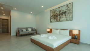 A modern bedroom with a large bed, bedside lamps, a gray sofa, and a large abstract painting on the wall.