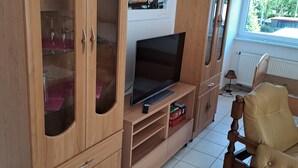 A living room with wooden cabinets, a flat-screen TV, and a leather armchair. - Vacation apartment in Twist, Dutch border, recreational area within walking distance (Twist)