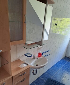 A bathroom with a white sink, a mirror, and a wooden cabinet. - Vacation apartment in Twist, Dutch border, recreational area within walking distance (Twist)
