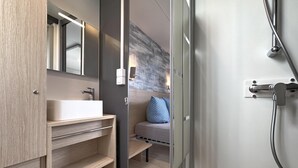 Une salle de bain moderne avec un meuble-lavabo en bois, un grand miroir et une douche dotée d’une porte en verre.
