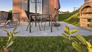 Un espace extérieur moderne aménagé avec une table et des chaises, une pergola et une structure en pierre.