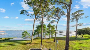 A wooden boardwalk leading to a dock by a lake, surrounded by trees and grassy areas. - Last Resort (Gulf Shores)