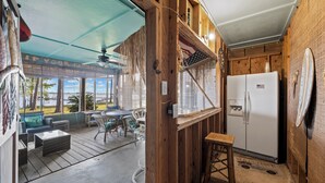 A wooden cabin with a patio area featuring outdoor seating, a refrigerator, and a ceiling fan. - Last Resort (Gulf Shores)
