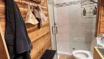 Un interior de madera con ducha, inodoro y perchero para toallas.