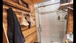 Een houten interieur met een douche, toilet en handdoekhouder.