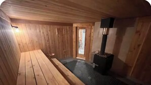 Een houten sauna met een bank, een klein raam en een sauna-oven.