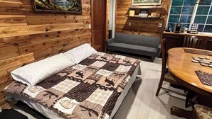 Een gezellige kamer met een bed, een bank, een eettafel en een plafondventilator.