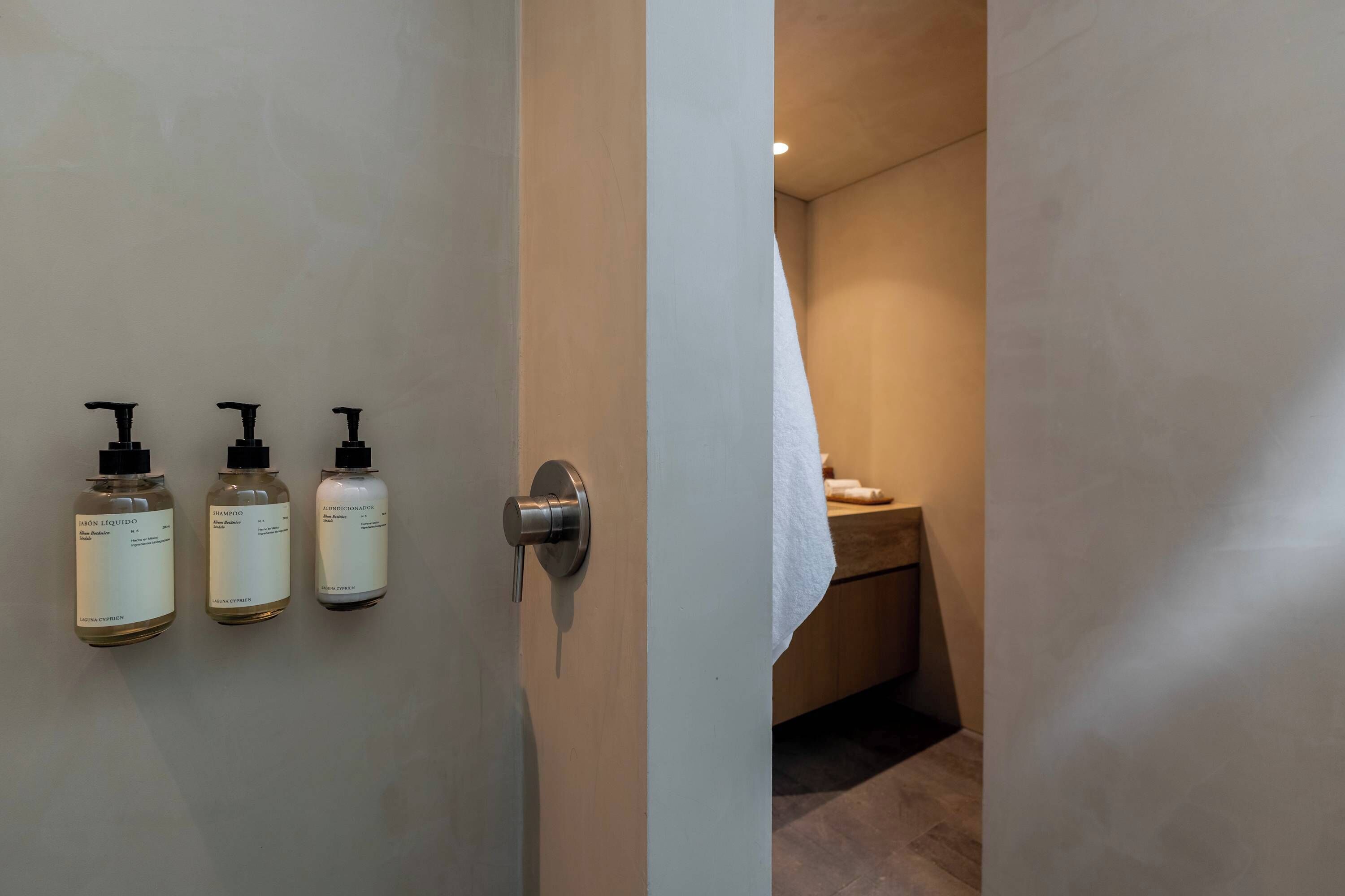 Ein Badezimmer mit drei Flüssigseifenflaschen an der Wand und einem Handtuch an einem Halter.