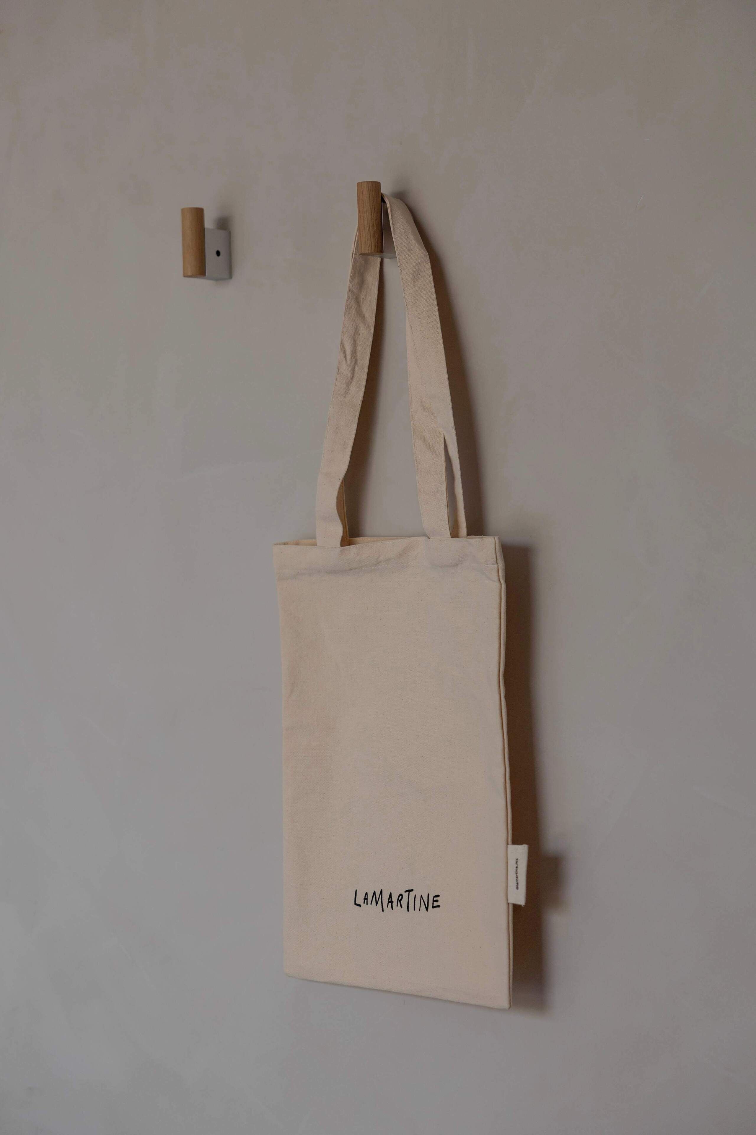 A beige canvas tote bag hanging on a wall.