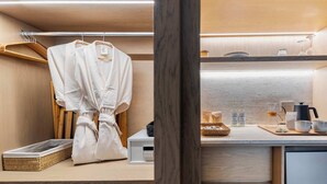 Une salle de bain moderne avec un meuble-lavabo en bois, un peignoir suspendu à un porte-manteau et une machine à café posée sur le comptoir.