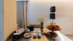 Une table de petit-déjeuner avec des viennoiseries, des bols de crème et un vase rempli de fleurs.