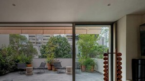 Un balcon avec des sièges d’extérieur, des plantes en pot et une vue sur les bâtiments.